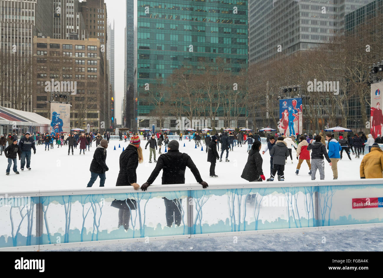 People ice skating in the snow at the Bryant Park Winter Village outdoors ice rink in New York City Stock Photo