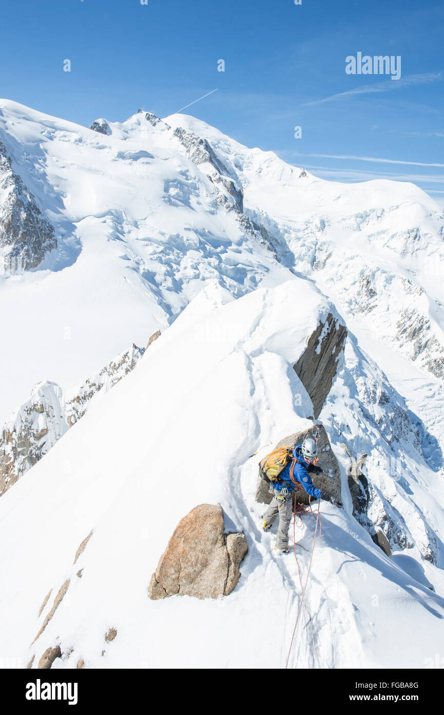 Mountain guide installing ropes to safely lead his client on the arete des Cosmiques in the Mont Blanc range Stock Photo