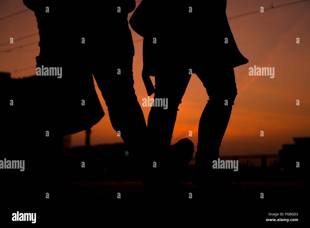 Low Section Of Silhouette People Walking On Footpath At Sunset Stock Photo