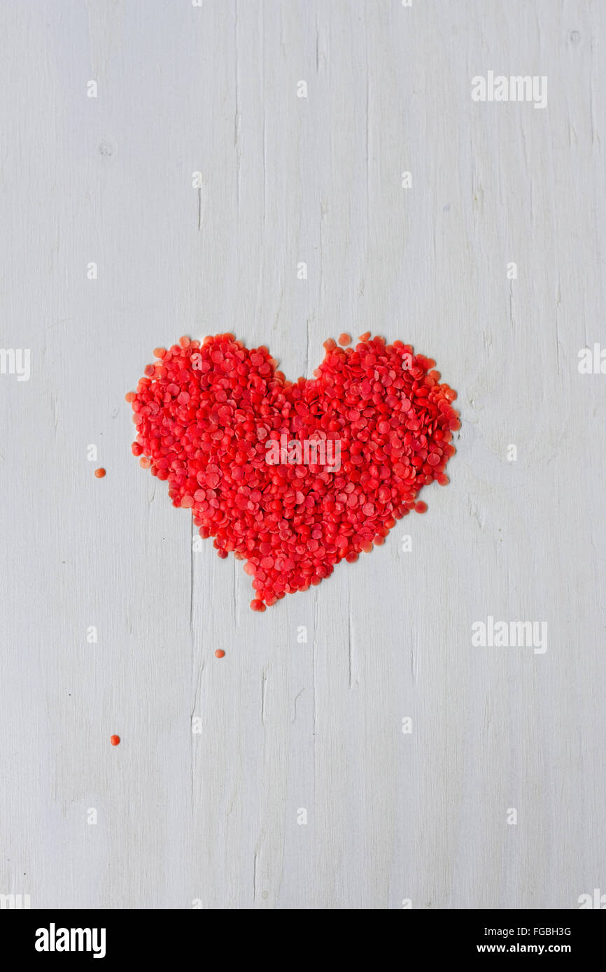 Heart Shape Made With Red Split Lentils Over White Wooden Table Stock Photo