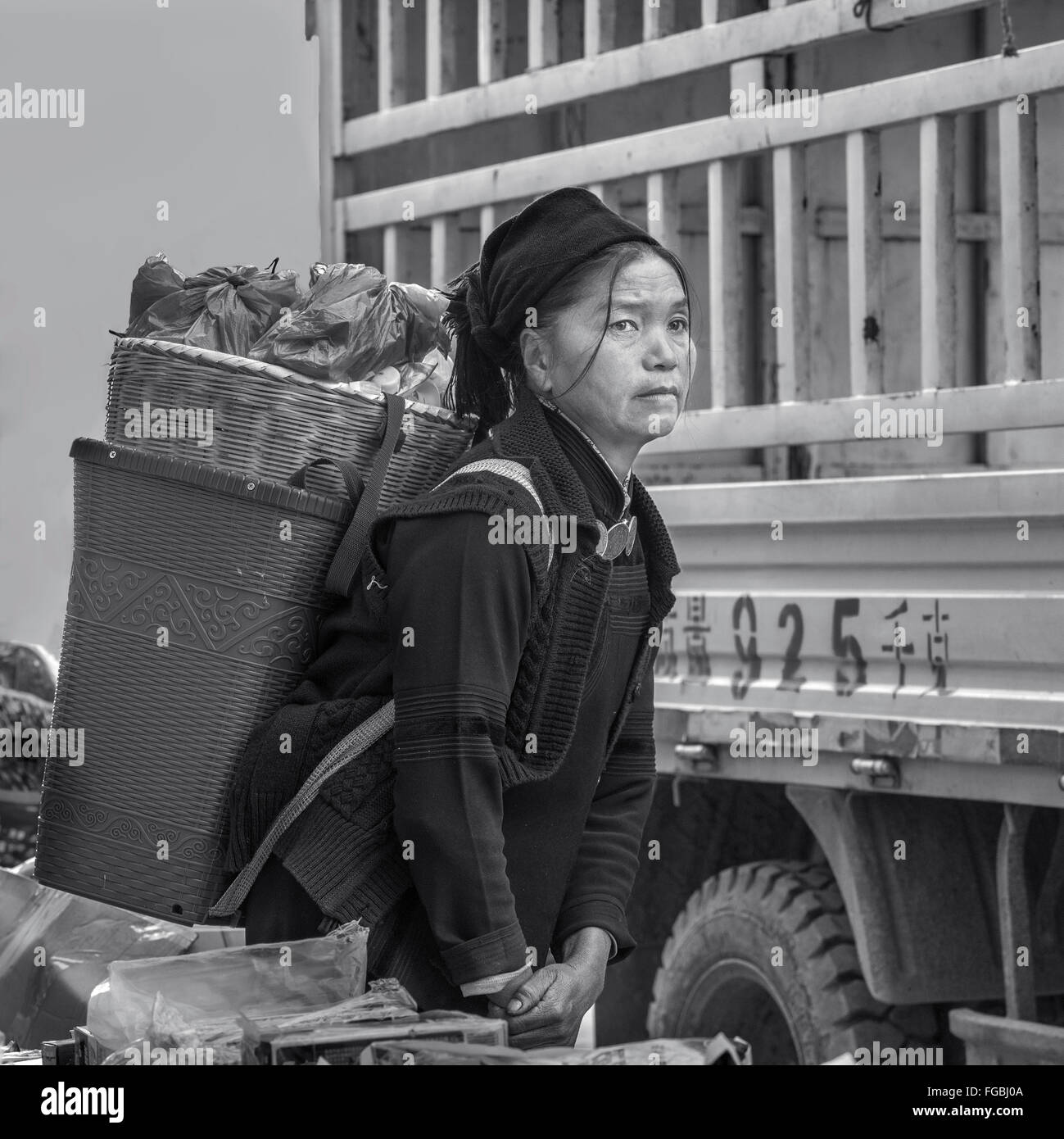 Tired woman with a heavy load, Niujiaozhai Market, Yunnan Province, China Stock Photo
