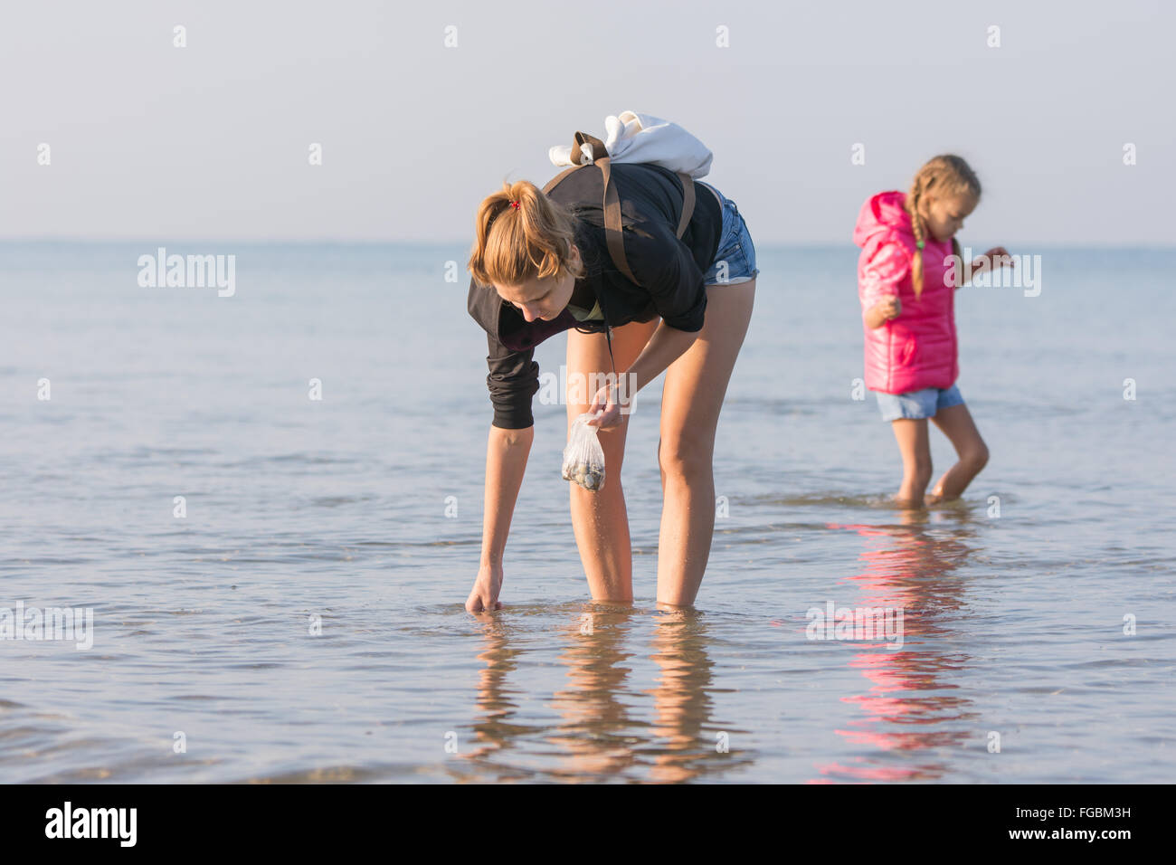 A young girl and a child of six shells collected in the sea early in the morning Stock Photo