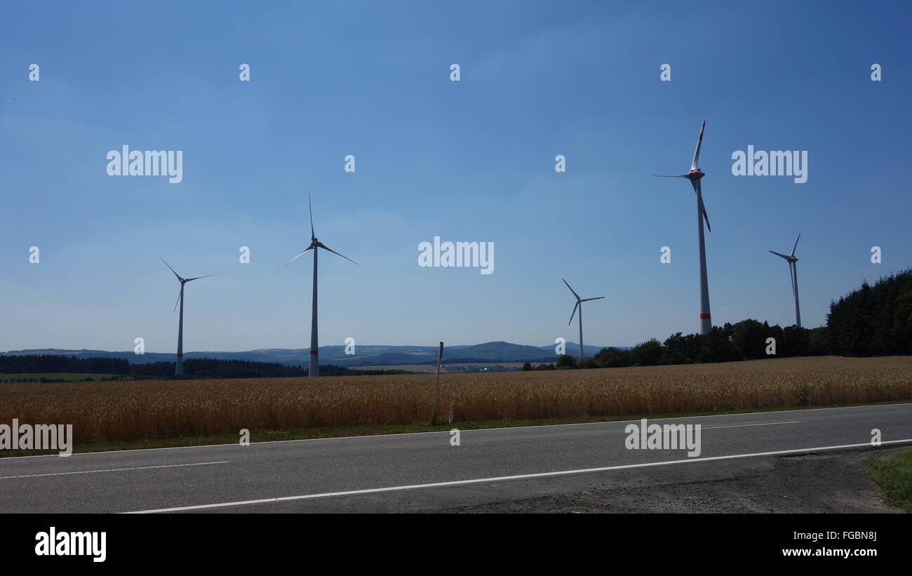Big windmills standing still a warm day in August , grain harvest has just begun. Eifel, Germany