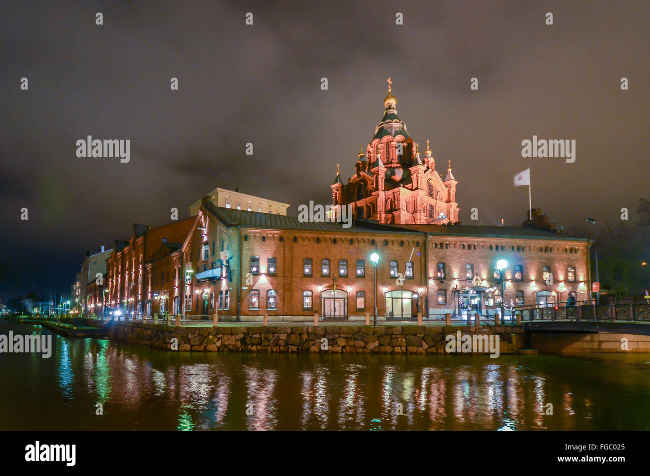 River In Front Of Illuminated Cathedral And Buildings Against Cloudy Sky Stock Photo