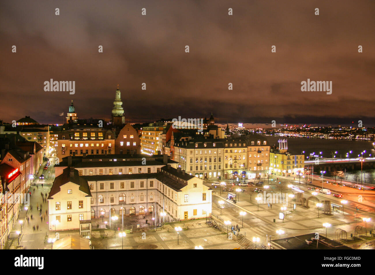 Illuminated Buildings On City Against Cloudy Sky At Night Stock Photo