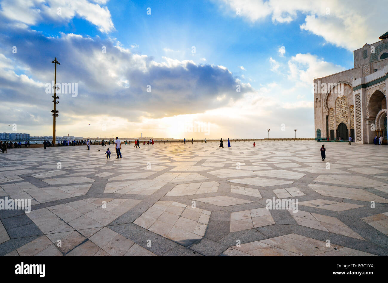 People At Mosque Hassan Ii Against Sky In City Stock Photo