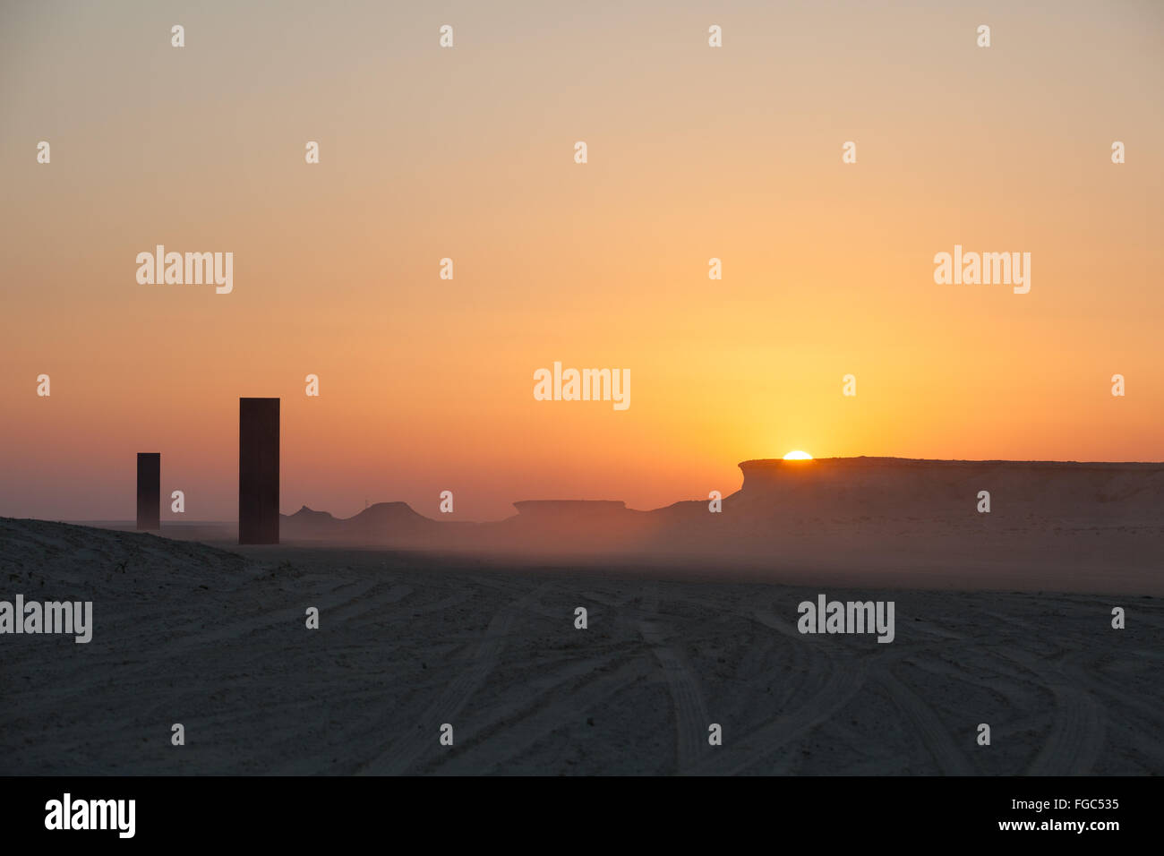 Sunset over East West West East in the Qatari desert. Public art installation by Richard Serra commissioned by Qatar Museums Authority. Stock Photo