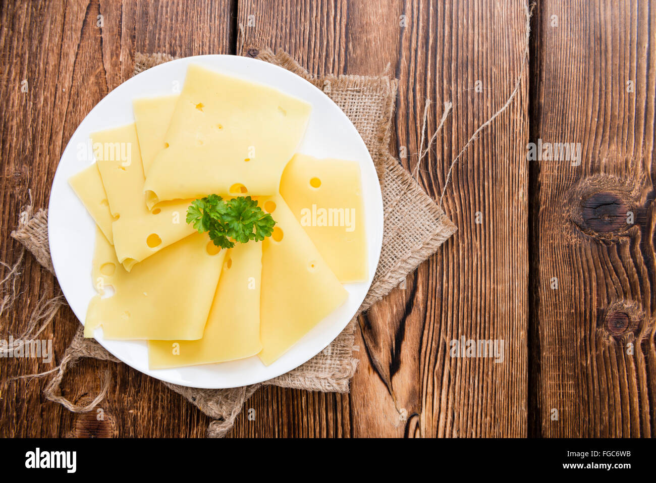 Sliced Cheese (detailed close-up shot) on rustic wooden background Stock Photo