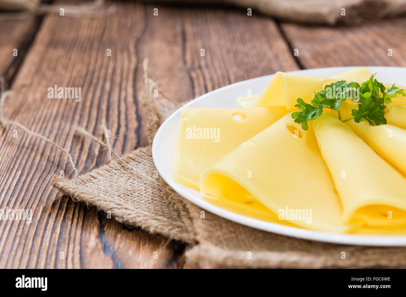 Sliced Cheese on rustic wooden background (close-up shot) Stock Photo