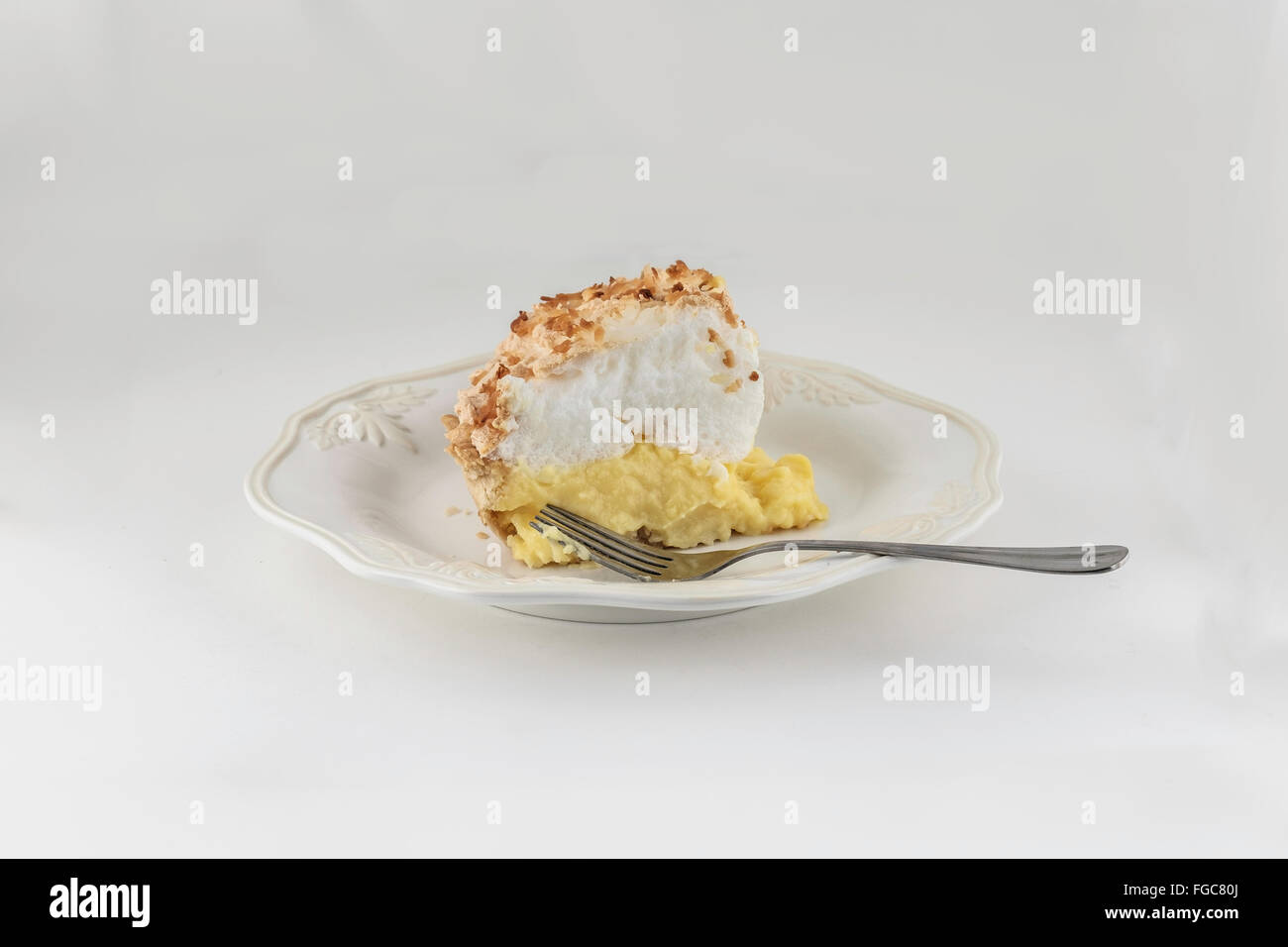 A slice of homemade freshly baked coconut cream meringue pie isolated on white. Stock Photo