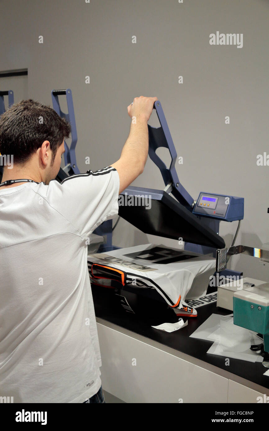 A shop assistant using a heat press to put a name and number on the back of a Valencia team