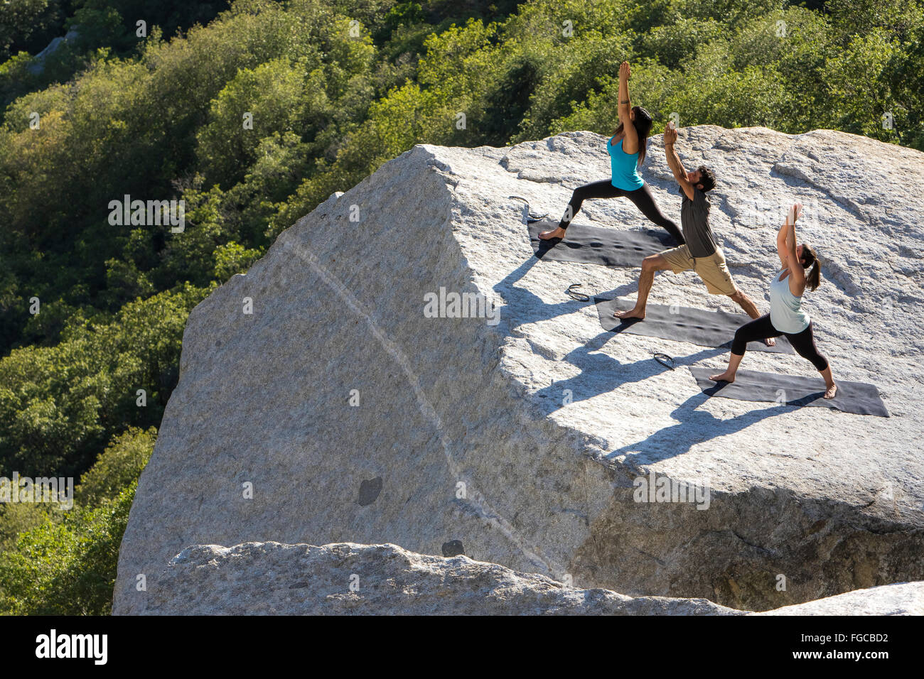 Three People Perform Yoga Stock Photo