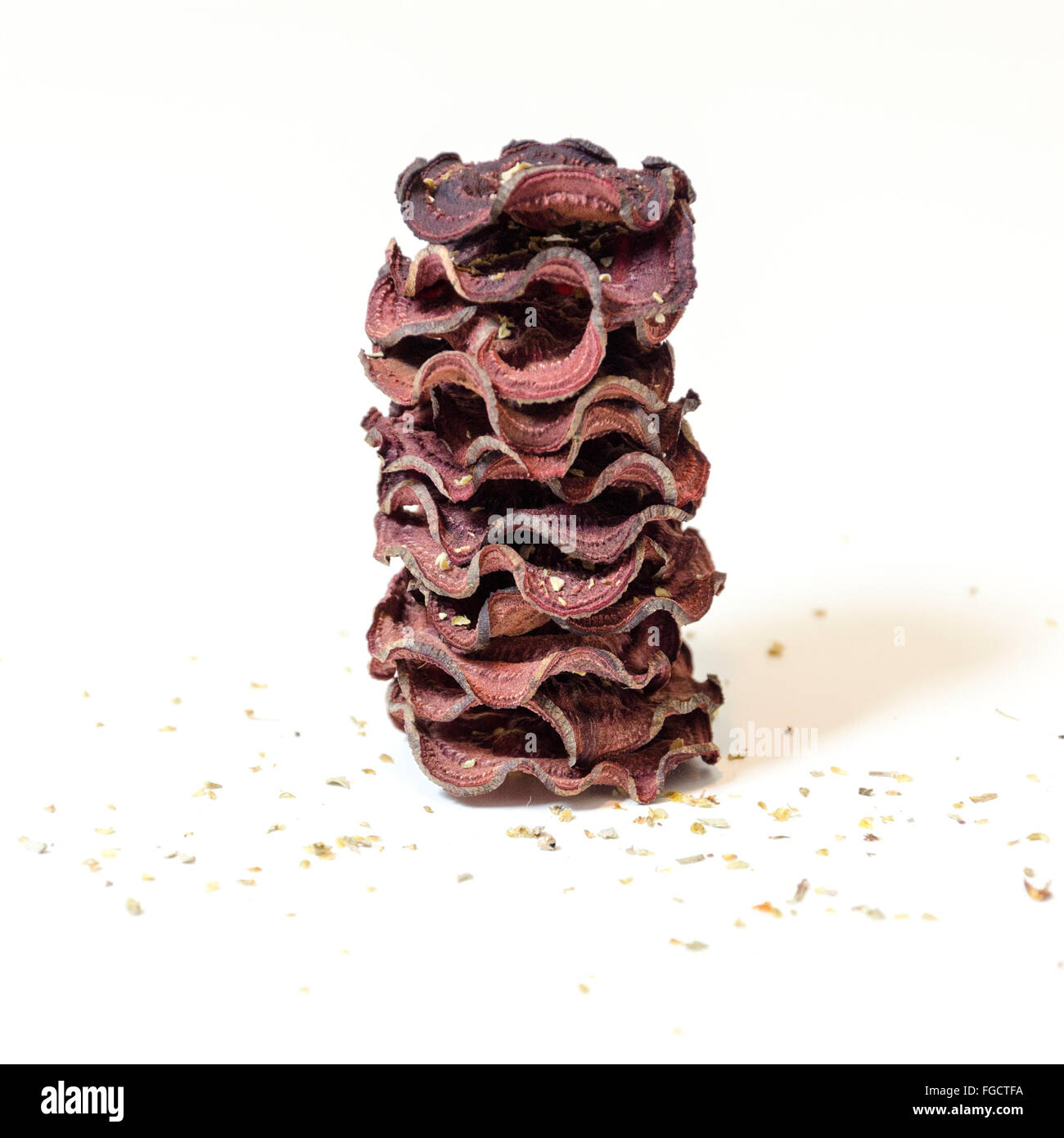 A stack of thin round beetroot chips baked in the oven with oregano and salt piled on white background. A healthy, vegetarian, v Stock Photo
