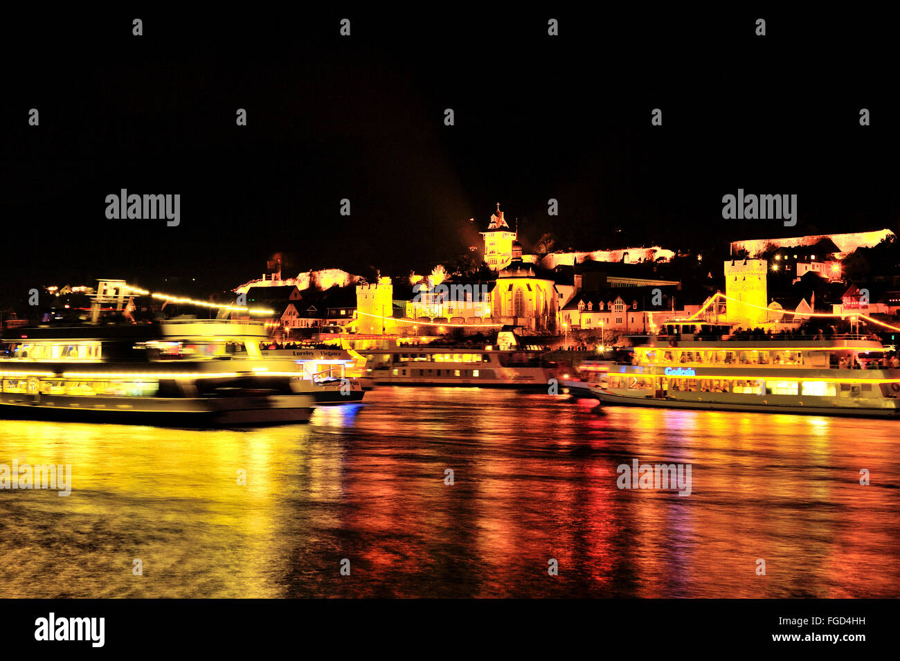 Illuminated town Oberwesel and light reflection at the Rhine bank for the festival of Rhein in Flammen with passing pleasure boats Stock Photo