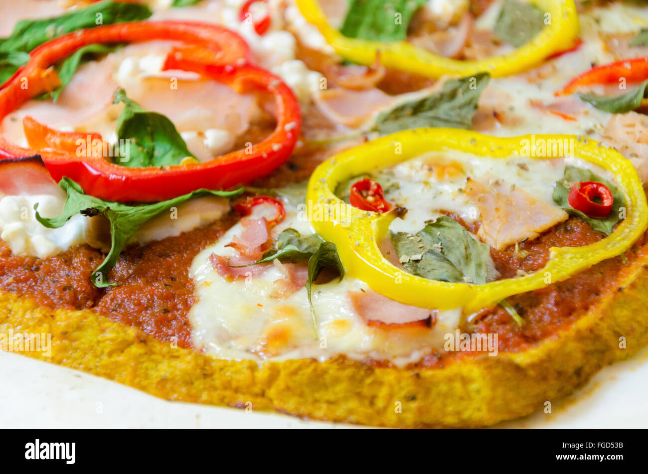 Oven baked cauliflower pizza crust topped with halloumi, cottage, mozzarella cheese, spinach, turkey, ham, peppers, chili, basil Stock Photo