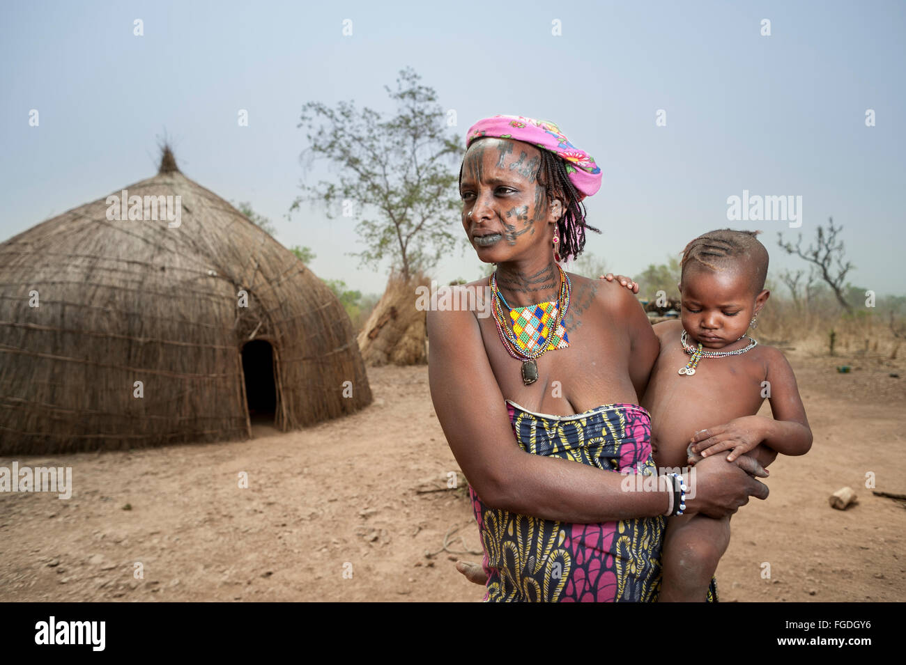 Portrait of a Mbororo woman with the typical scarification on her face holding her child. Stock Photo