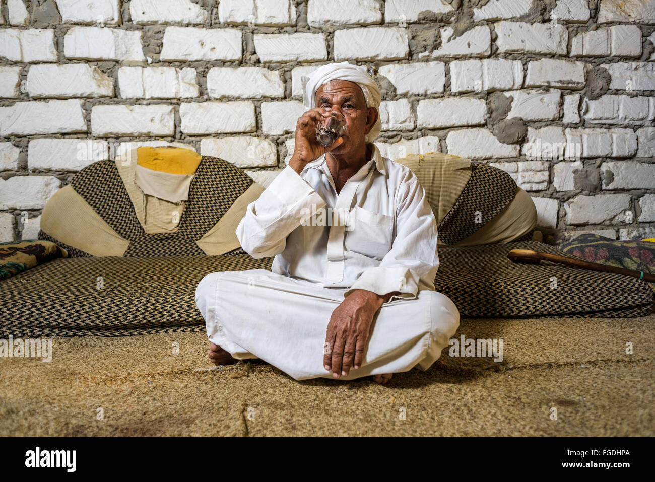 Old Egyptian man sitting on the floor drinking tea. Stock Photo