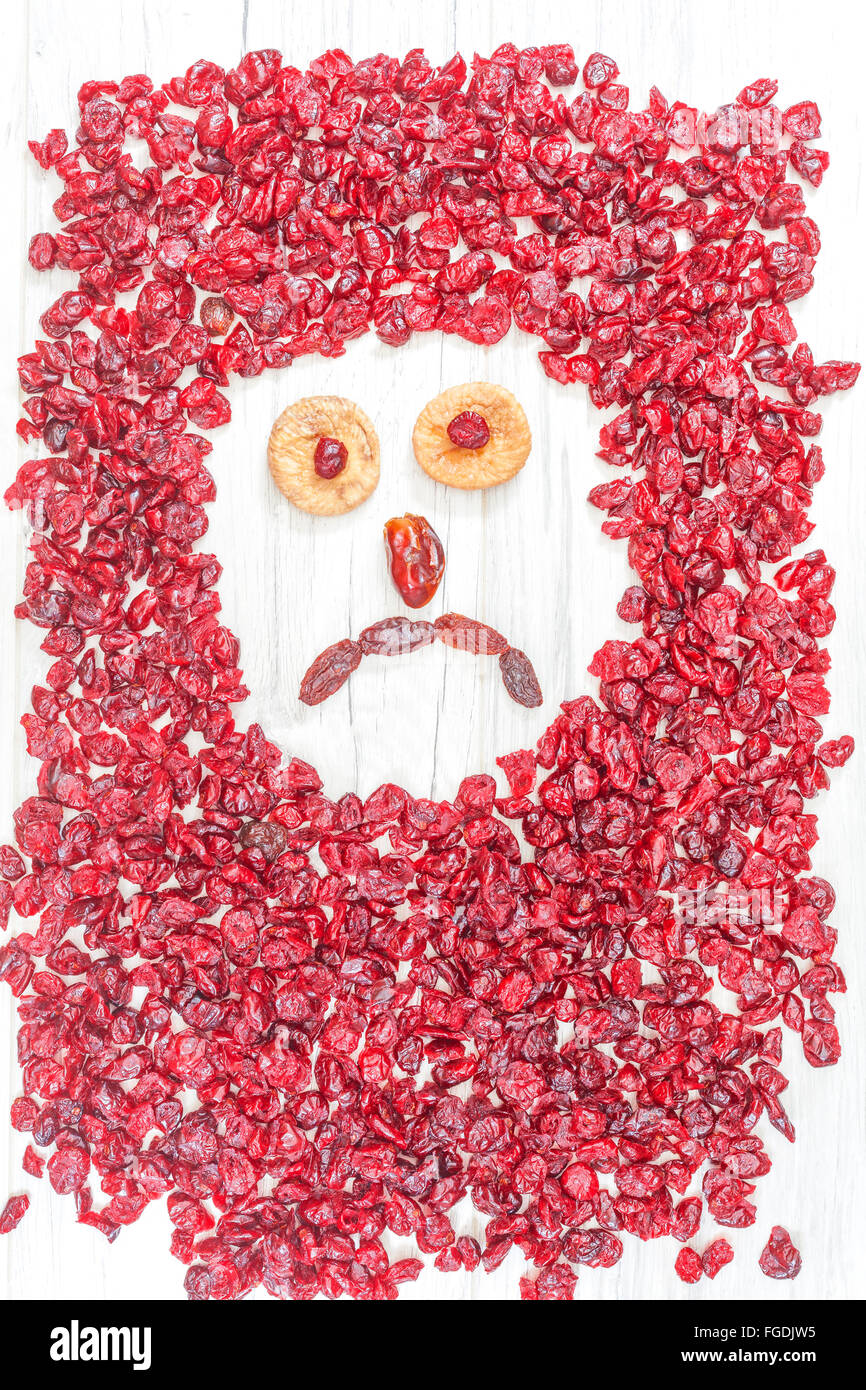 Sad face made of dried fruits on white wooden background. Stock Photo