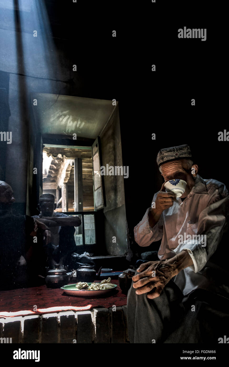 Uigur people eating in a small, dark restaurant. Stock Photo