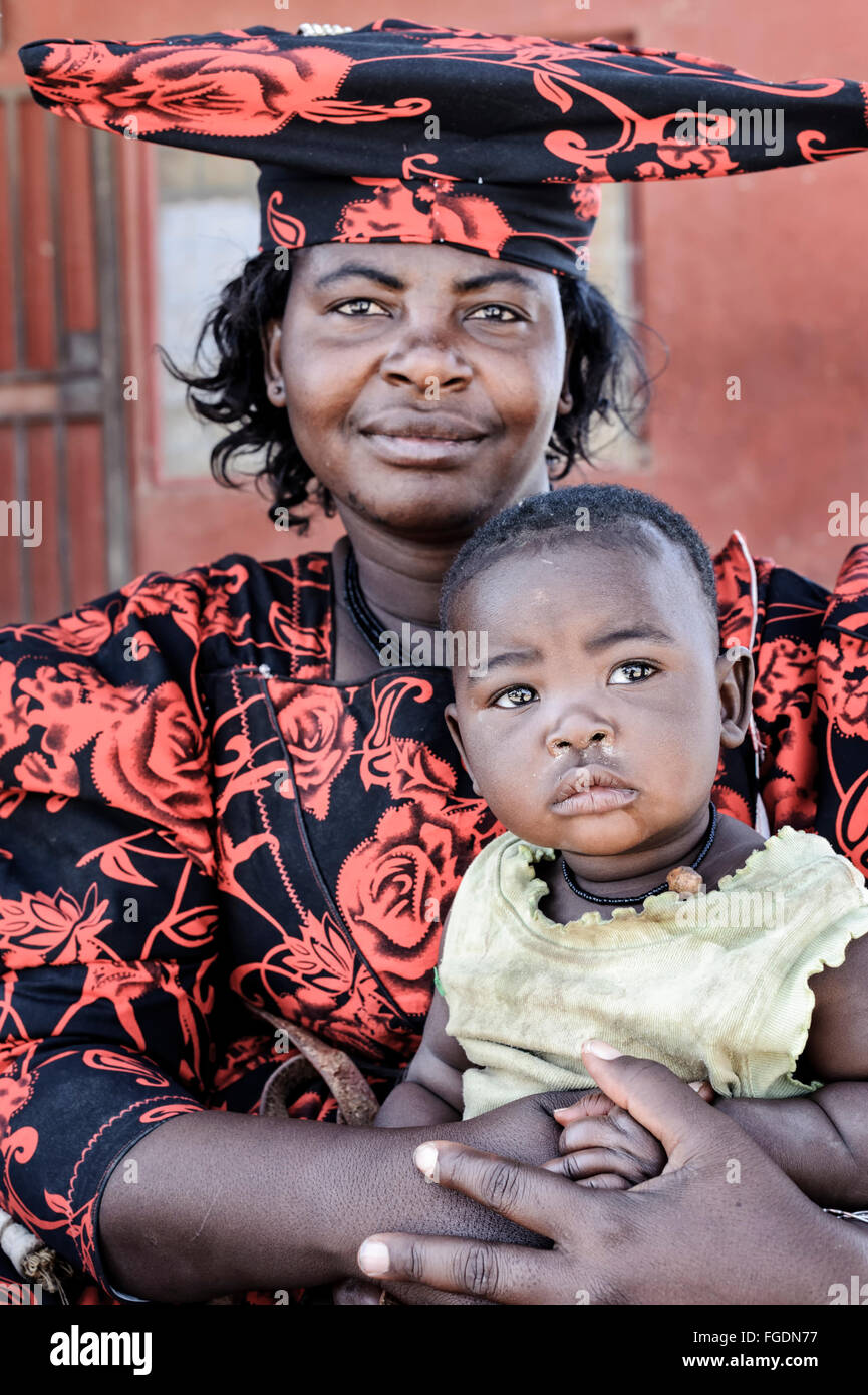 Portrait of a Herero woman with traditional attire holding her child. Stock Photo