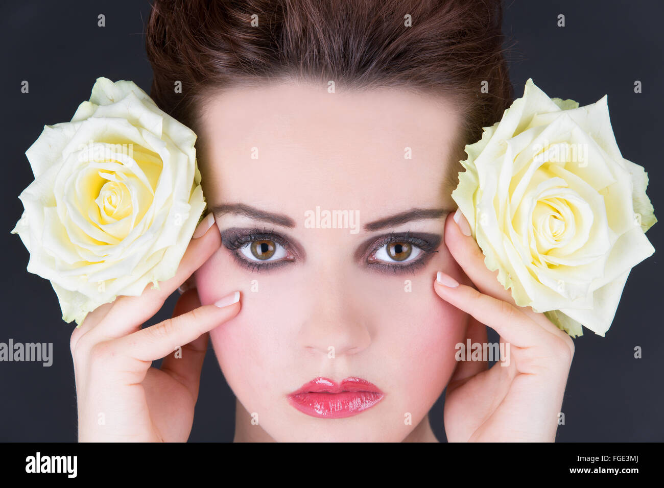 Young woman holding two yellow roses laterally nex Stock Photo