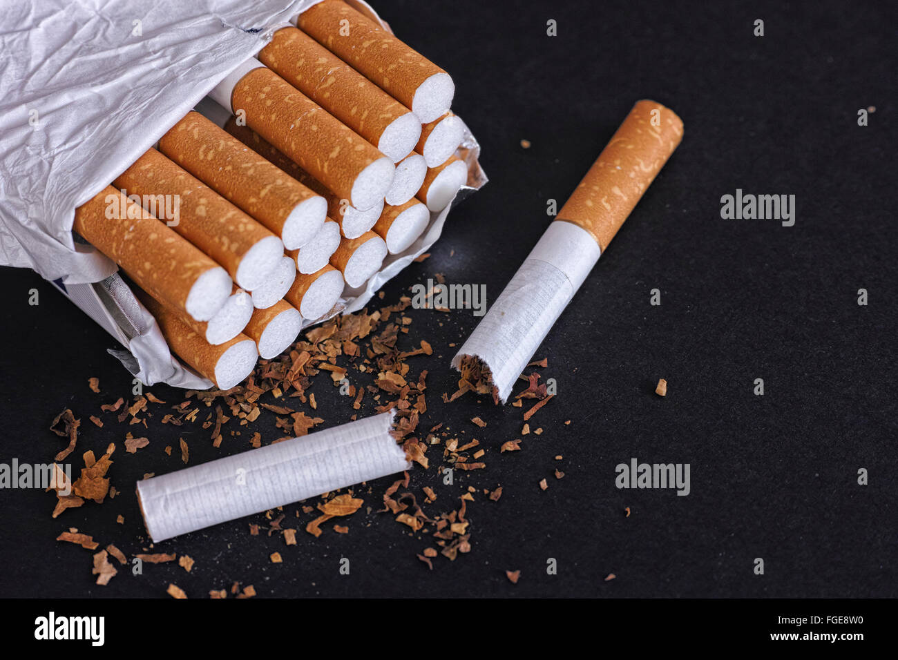 Open cigarette pack and one broken cigarette. Black background. Close up. Stock Photo