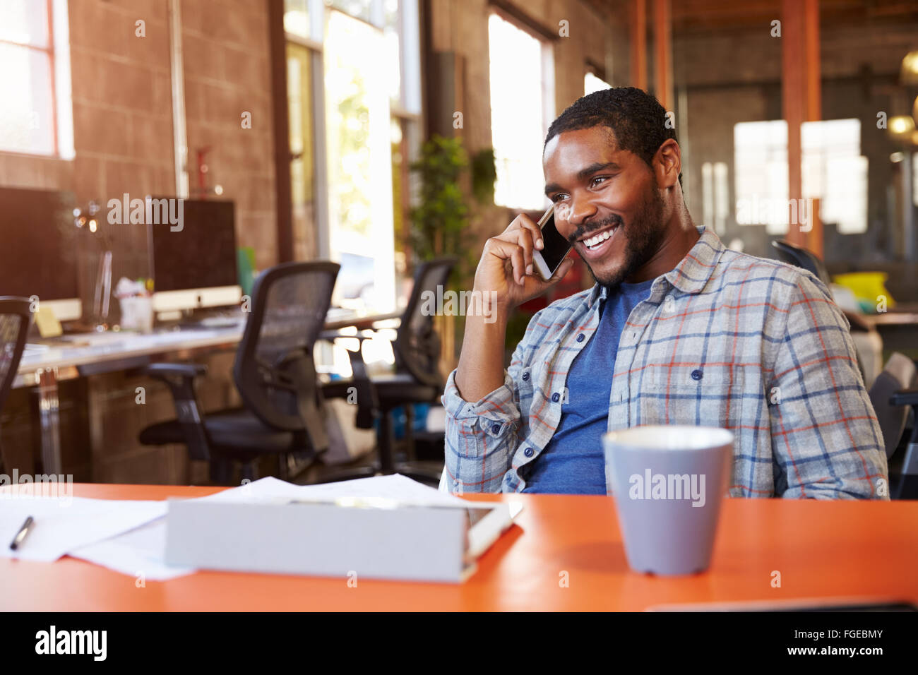 Designer Sitting At Meeting Table Talking On Mobile Phone Stock Photo ...