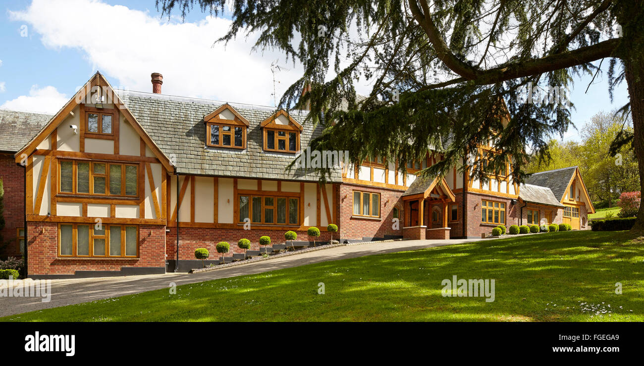 NeoTudor exterior of two storied house behind tree with grass