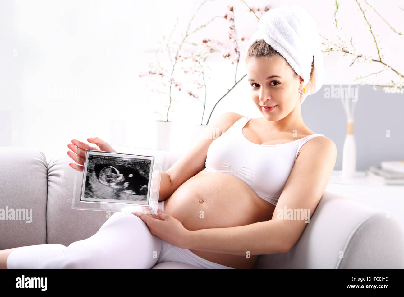 Pregnant woman showing ultrasound baby . Young expectant mother ultrasound shows the baby sitting on the sofa Stock Photo