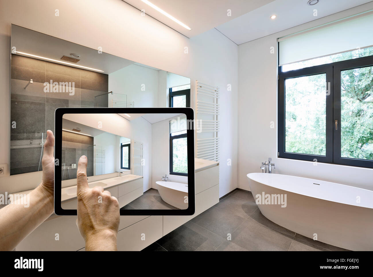 Mobile device with man hands taking picture in  tiled bathroom with windows towards garden Stock Photo