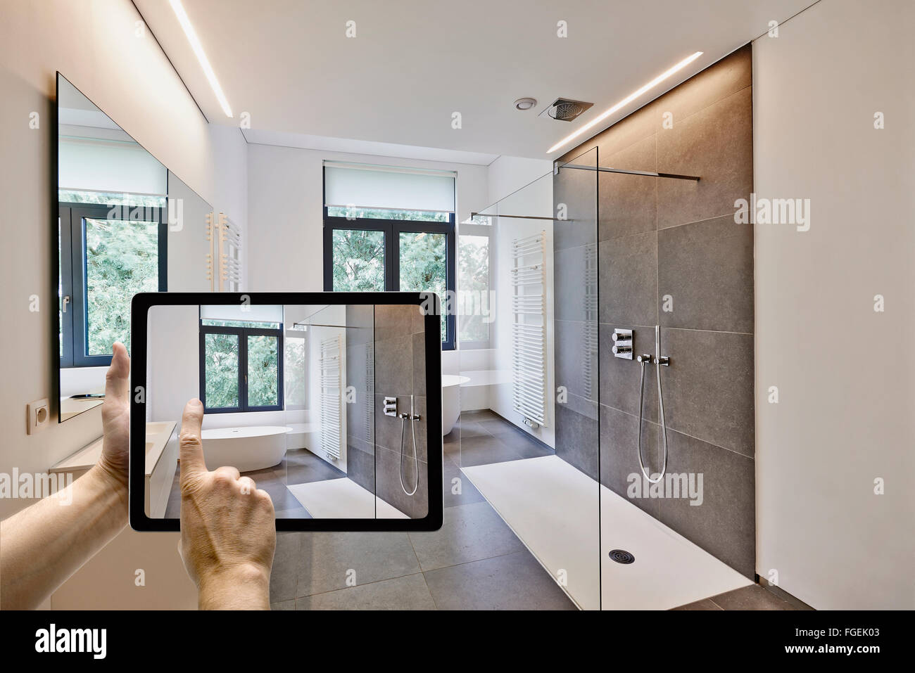 Mobile device with man hands taking picture in  tiled bathroom with windows towards garden Stock Photo