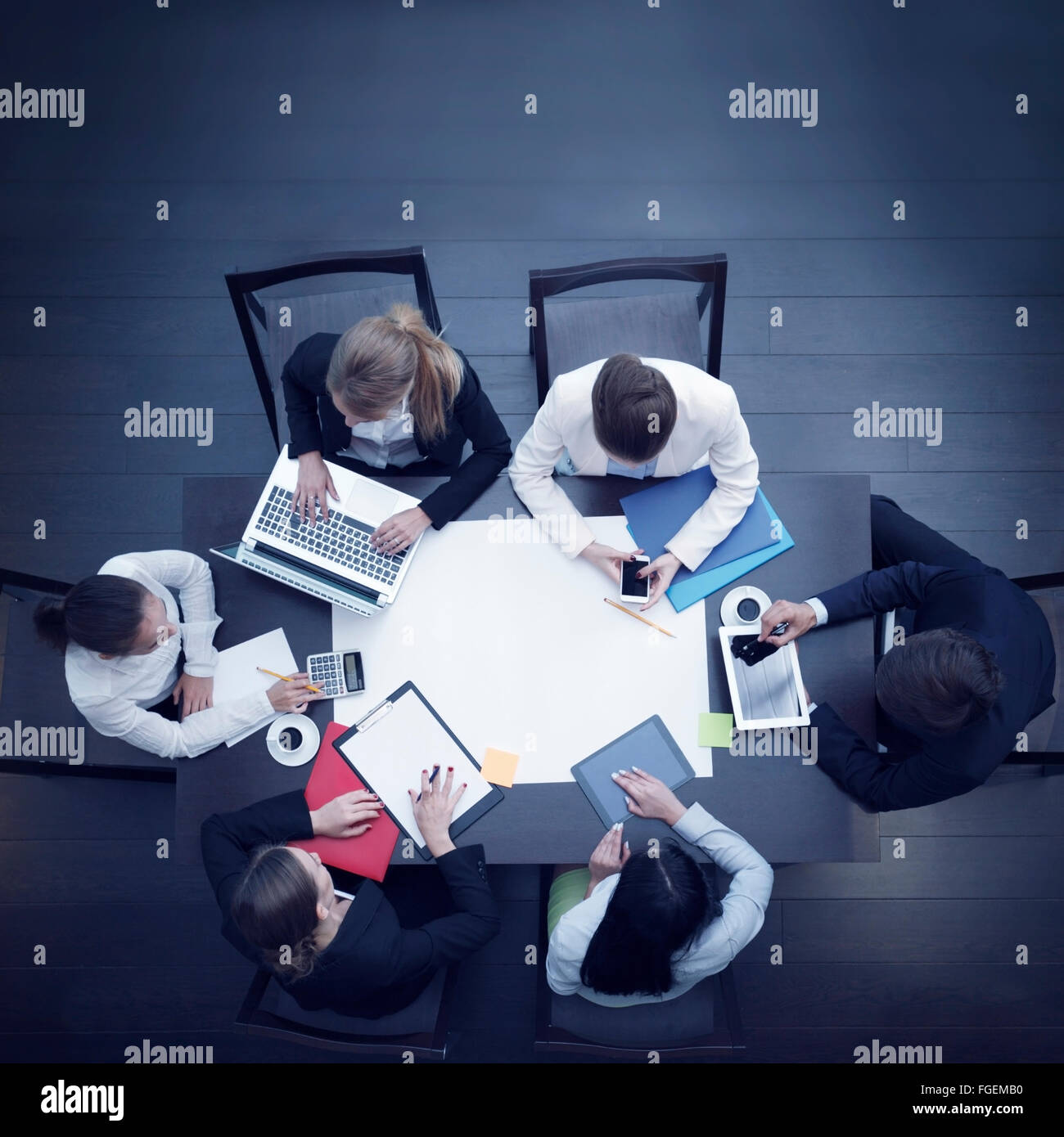 Business workplace with people, cup of coffee, digital tablet, smartphone, papers and various office objects on table Stock Photo