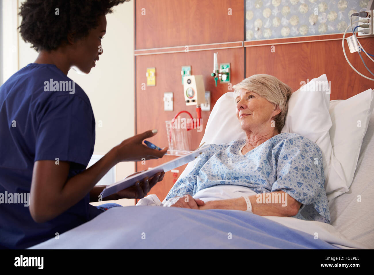 Nurse Talking To Senior Female Patient In Hospital Bed Stock Photo - Alamy