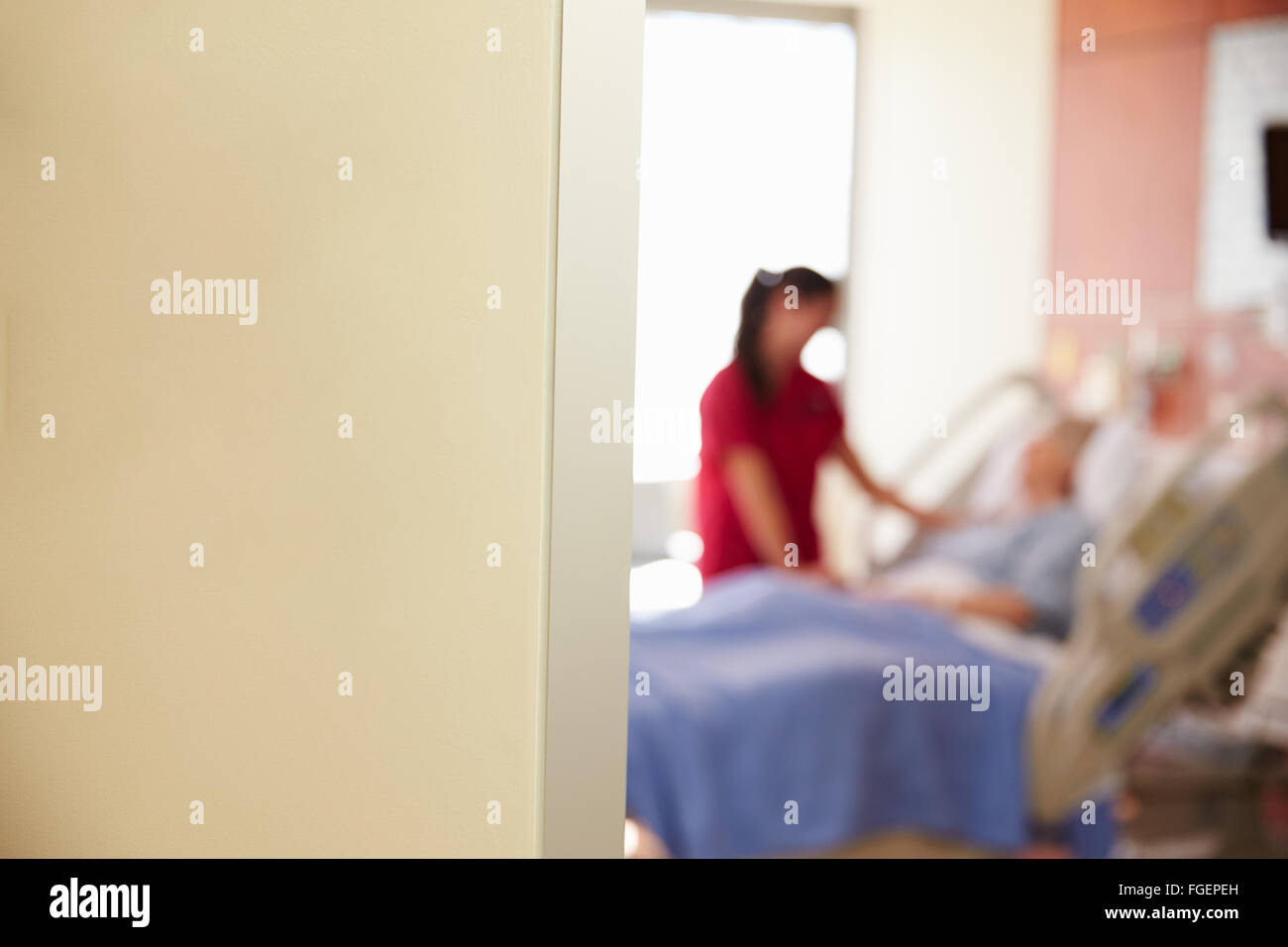 Focus On Hospital Room Sign With Nurse Talking To Patient Stock Photo