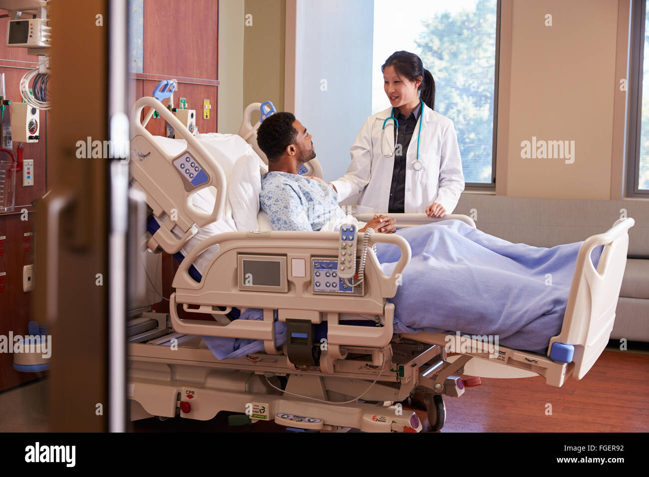 Female Doctor Talking To Male Patient In Hospital Bed Stock Photo - Alamy