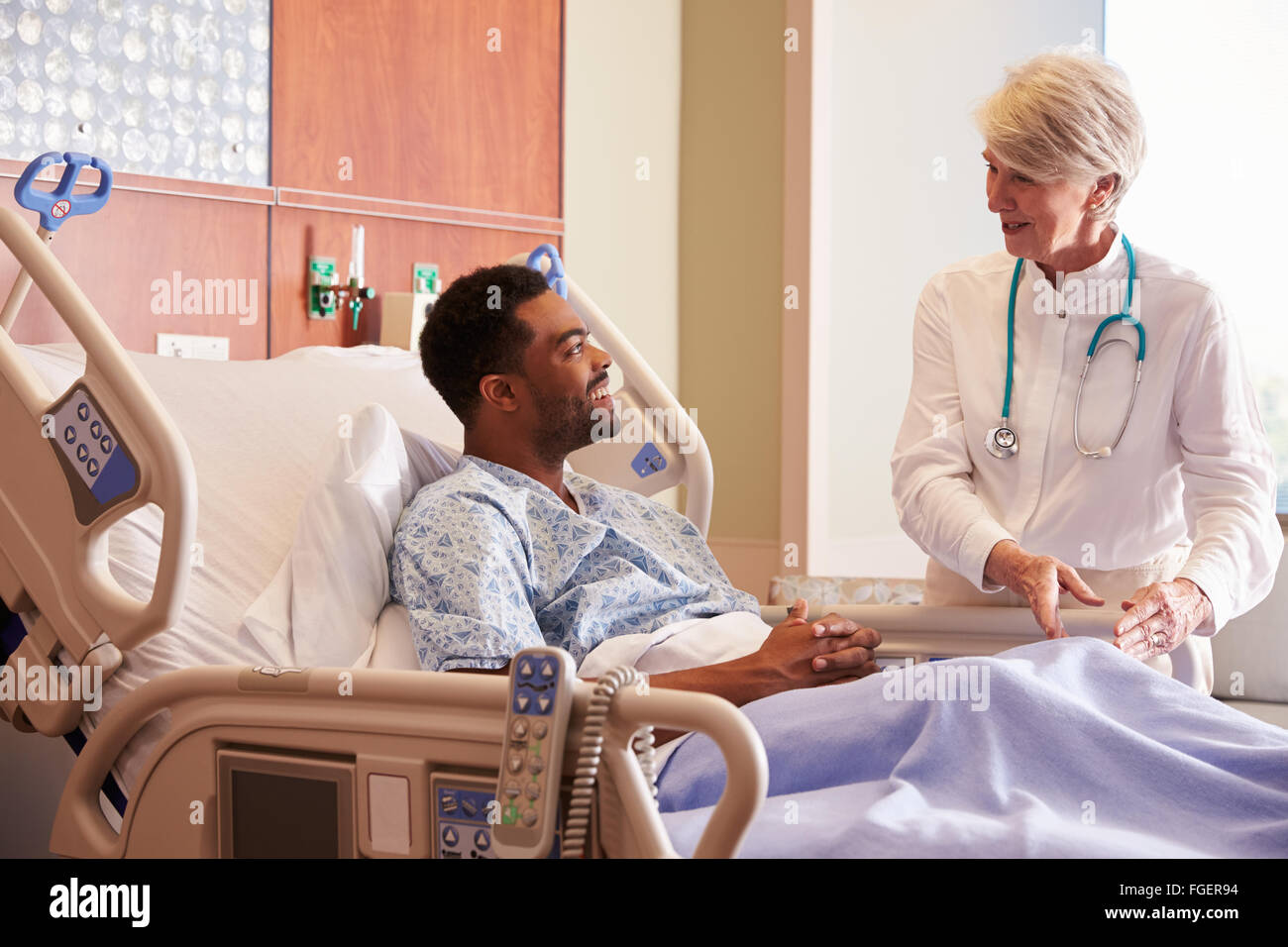 Female Doctor Talking To Male Patient In Hospital Bed Stock Photo - Alamy