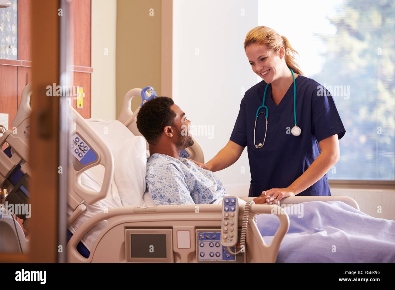 Female Doctor Talking To Male Patient In Hospital Bed Stock Photo - Alamy