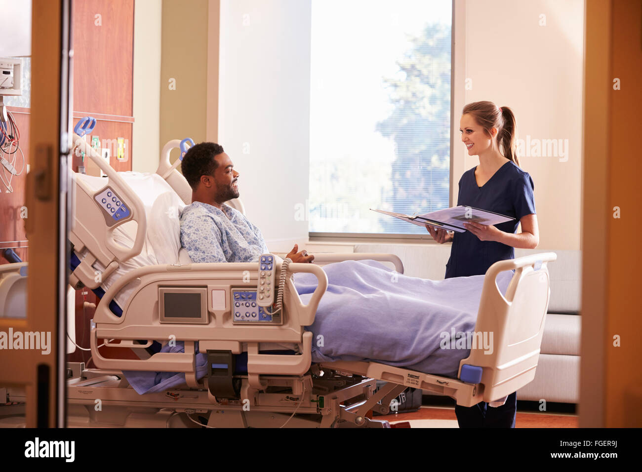 Female Doctor Talking To Male Patient In Hospital Bed Stock Photo - Alamy