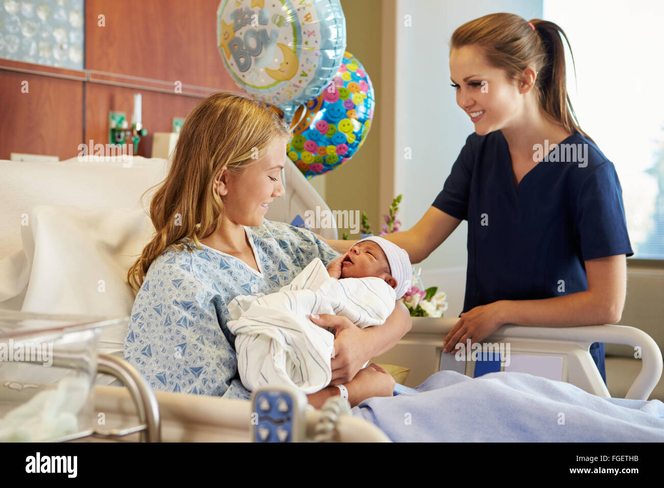Teenage Girl With Nurse Holding Newborn Baby In Hospital Stock Photo