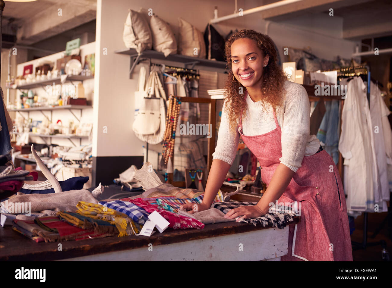 Female Sales Assistant Arranging Textiles In Homeware Store Stock Photo