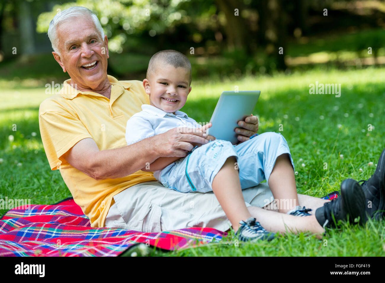grandfather and child in park using tablet Stock Photo