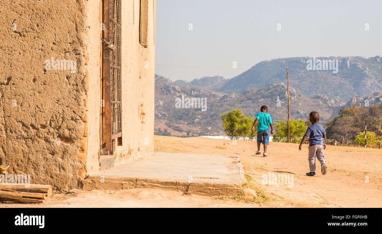 Two boys walk through their Zimbabwean village Stock Photo