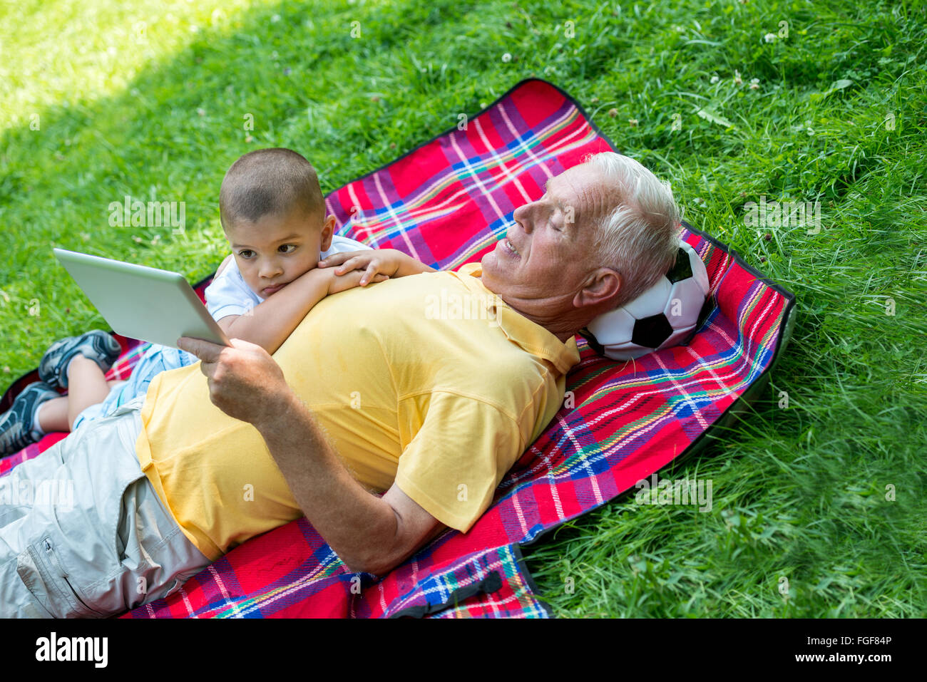 grandfather and child in park using tablet Stock Photo
