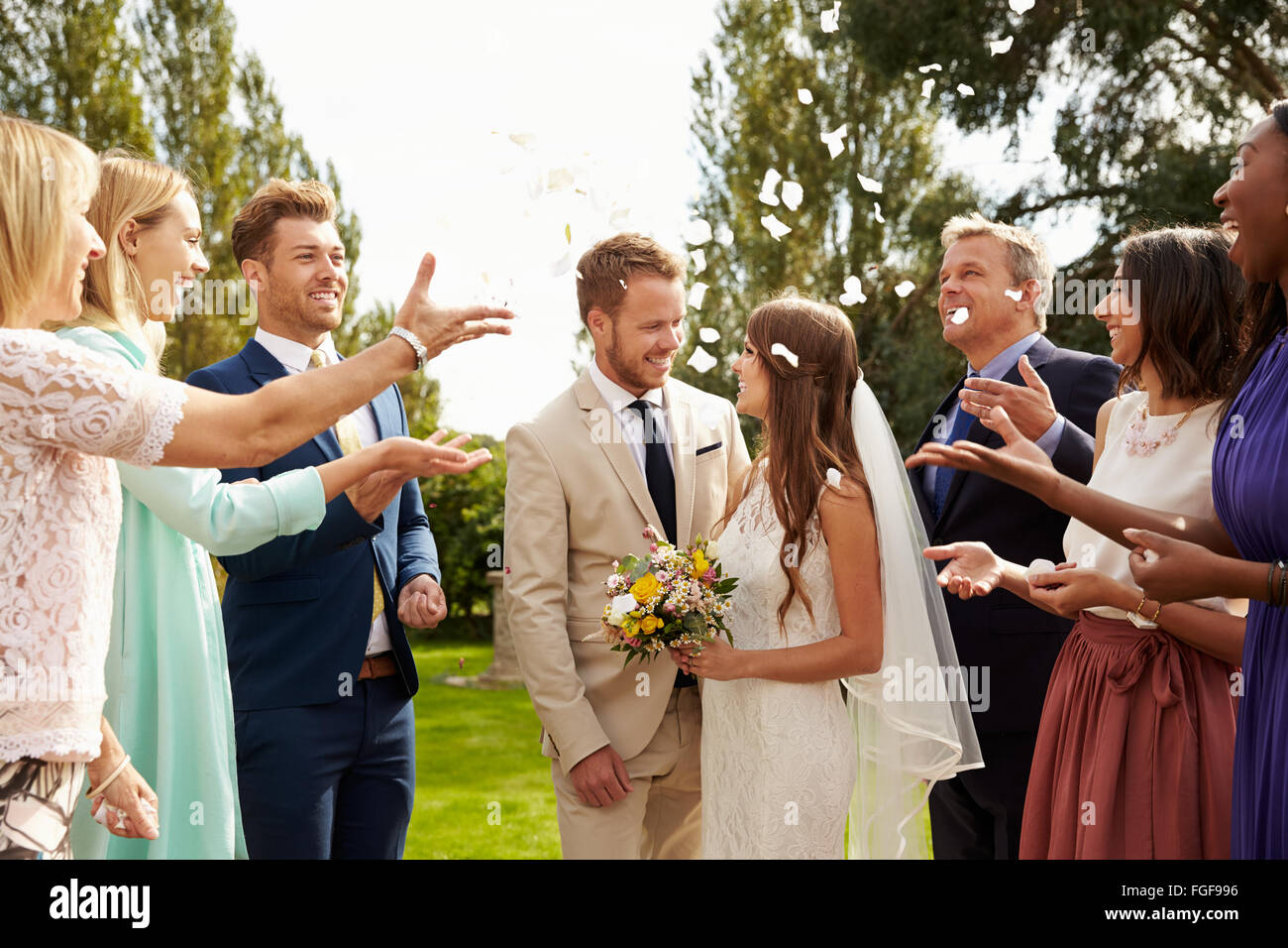 Guests Throwing Confetti Over Bride And Groom At Wedding Stock Photo Alamy