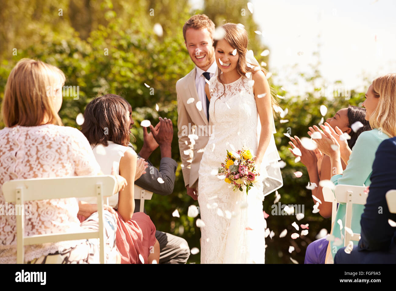 Guests Throwing Confetti Over Bride And Groom At Wedding Stock Photo