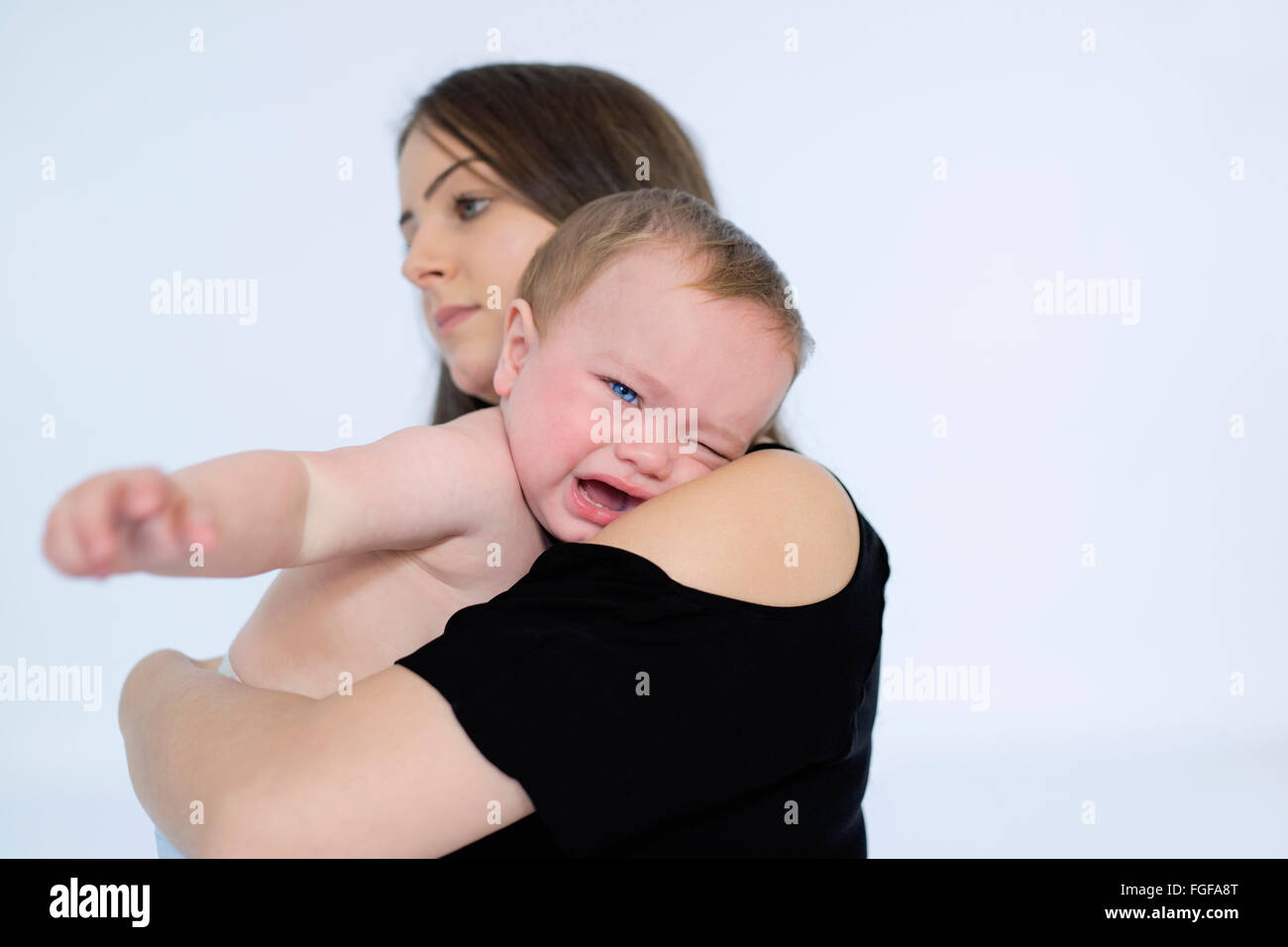 Mother holding baby son in arms crying Stock Photo