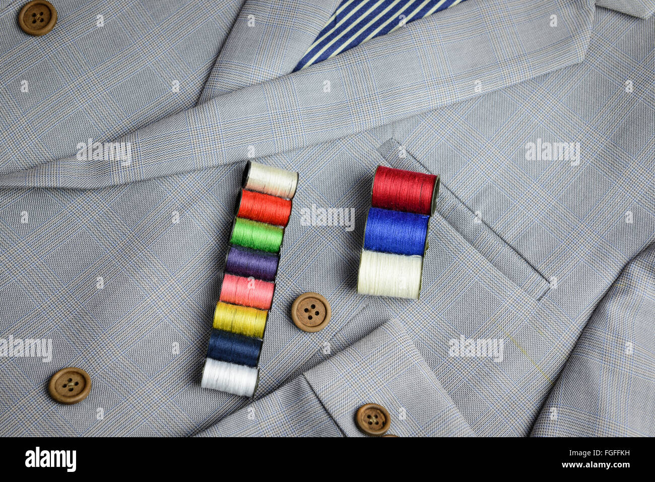 small coil of colorful thread stacking on grey suit, plaid texture ...