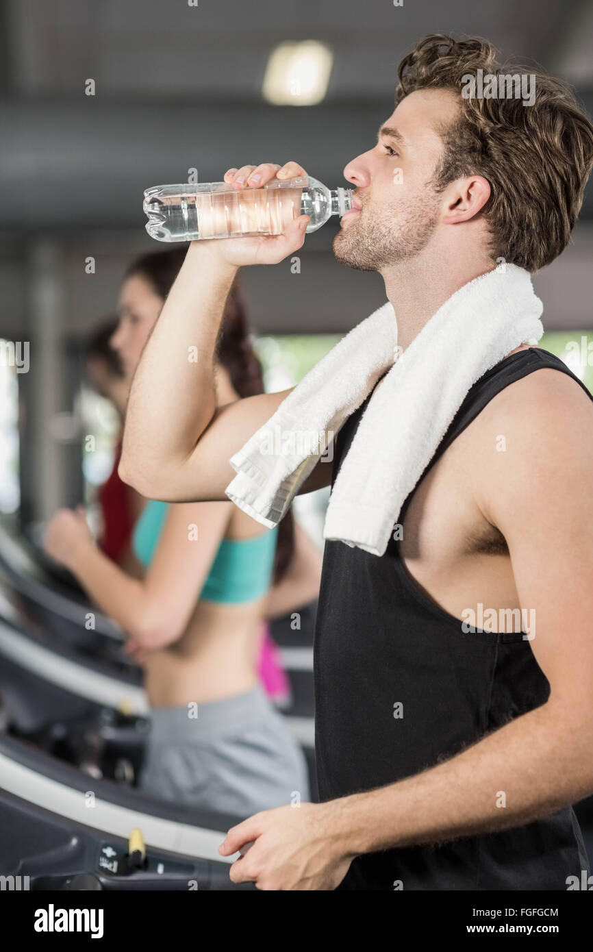 Athletic man drinking water while running on treadmill Stock Photo Alamy