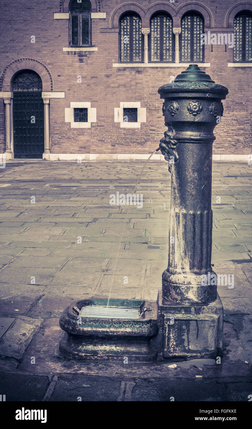 Antique standpipe in Venice with venetian architecture in the background Stock Photo