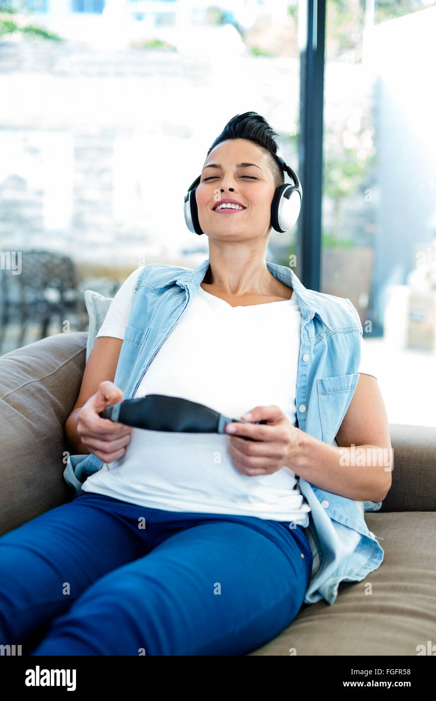 Pregnant woman listening to music on sofa Stock Photo - Alamy